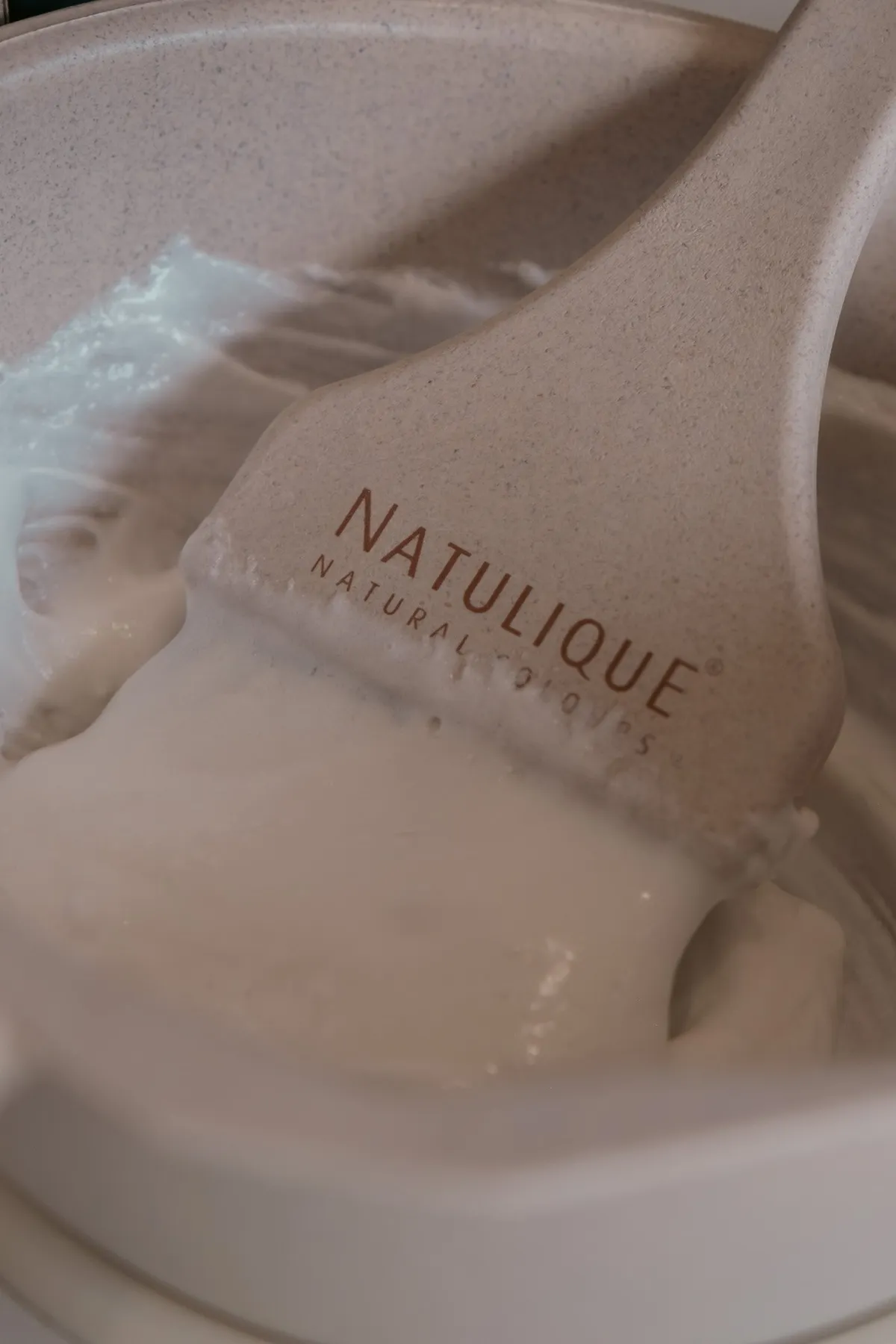 A Natulique brush resting in a bowl of freshly mixed hair colour